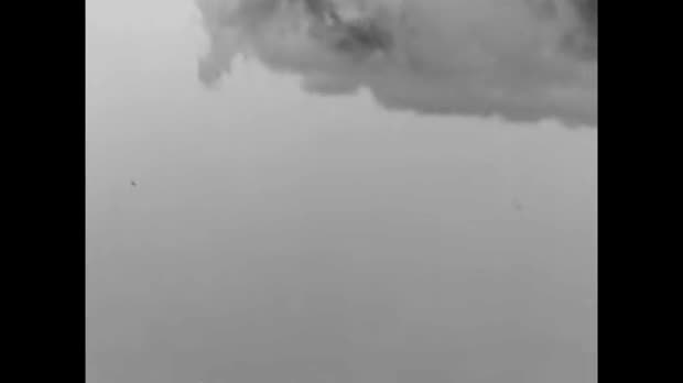 Thermal video frame showing two small dark objects against a gray sky below clouds